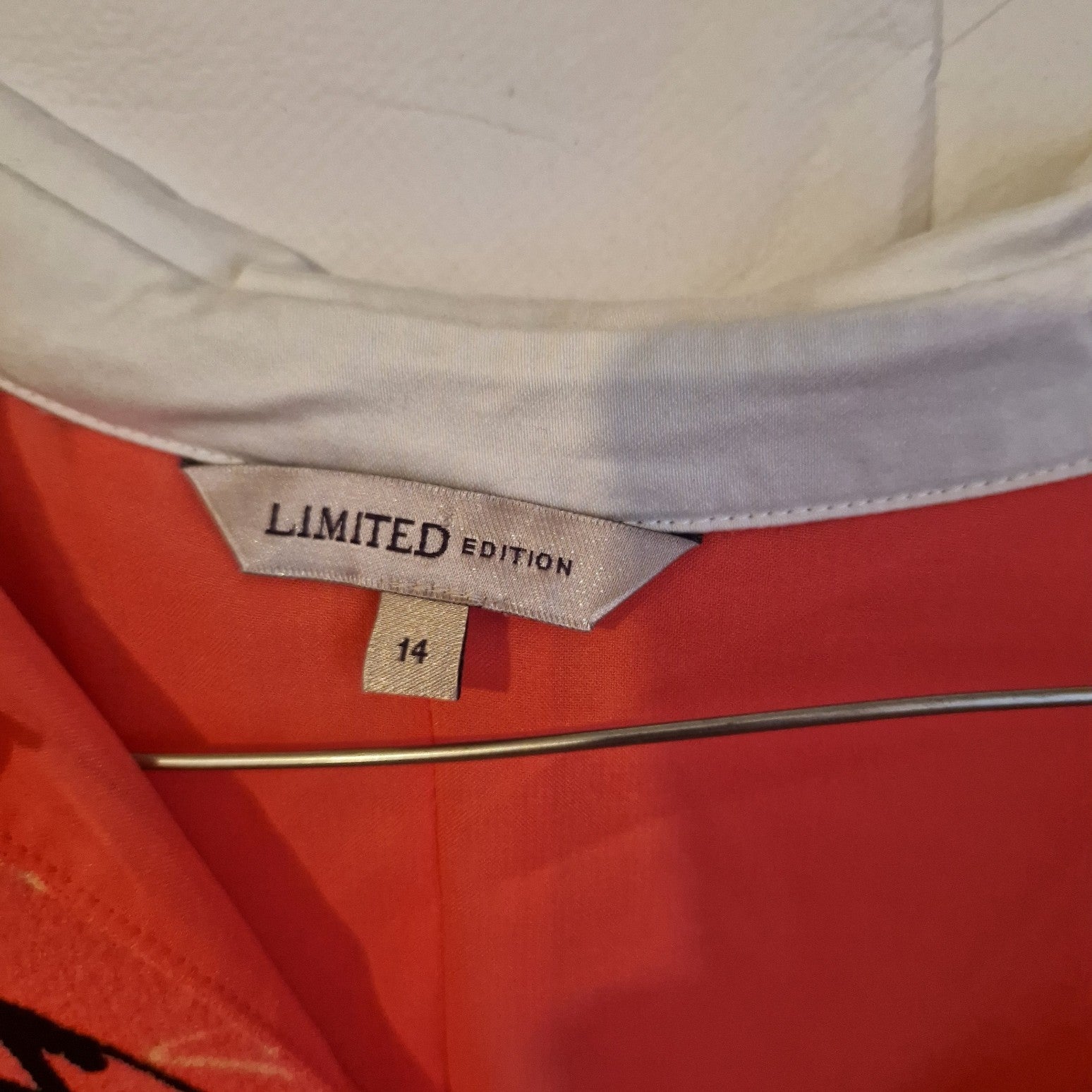 A close-up of the inner neck label on a pink floral Marks and Spencer dress, size 14.