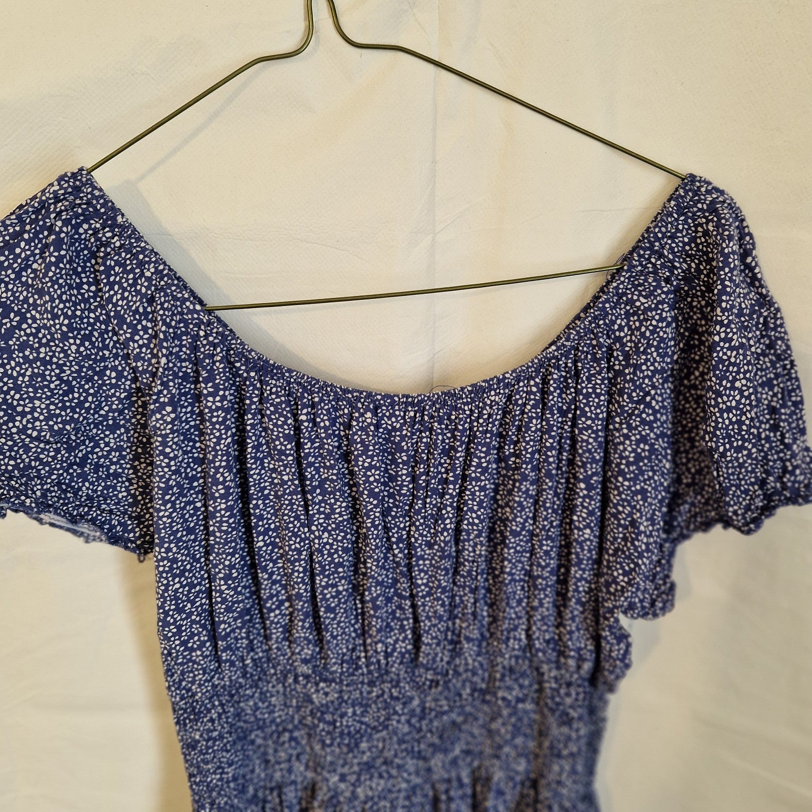 A blue knee-length dress with a white floral pattern, short sleeves, and a gathered neckline.