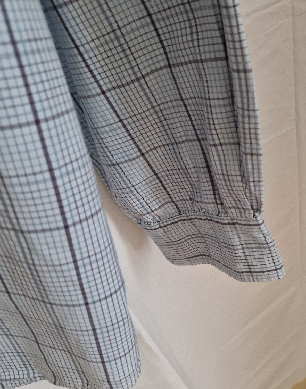 A long-sleeved Timberland shirt in a grey and blue check pattern with a buttoned cuff.