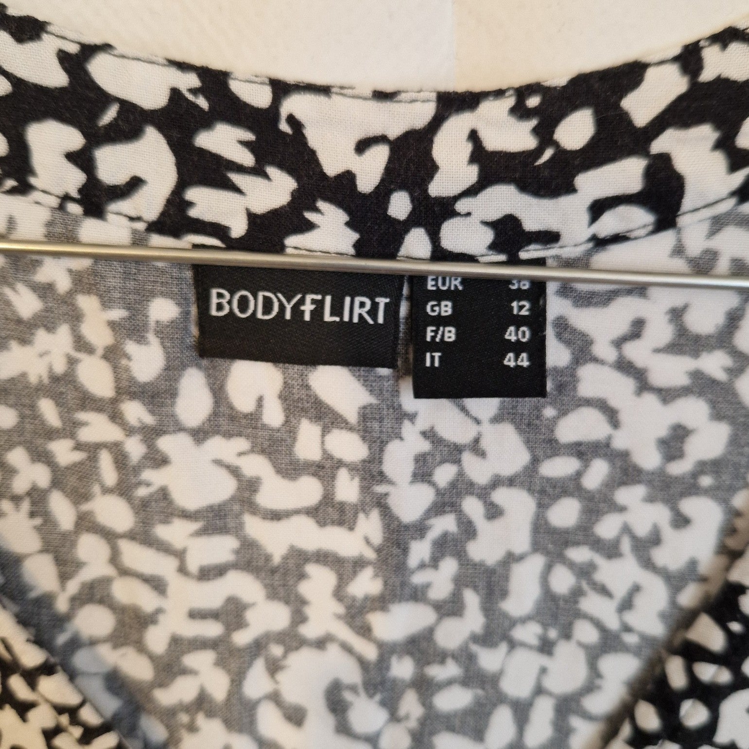 A close-up of the Bodyflirt brand label on a black and white floral print dress.