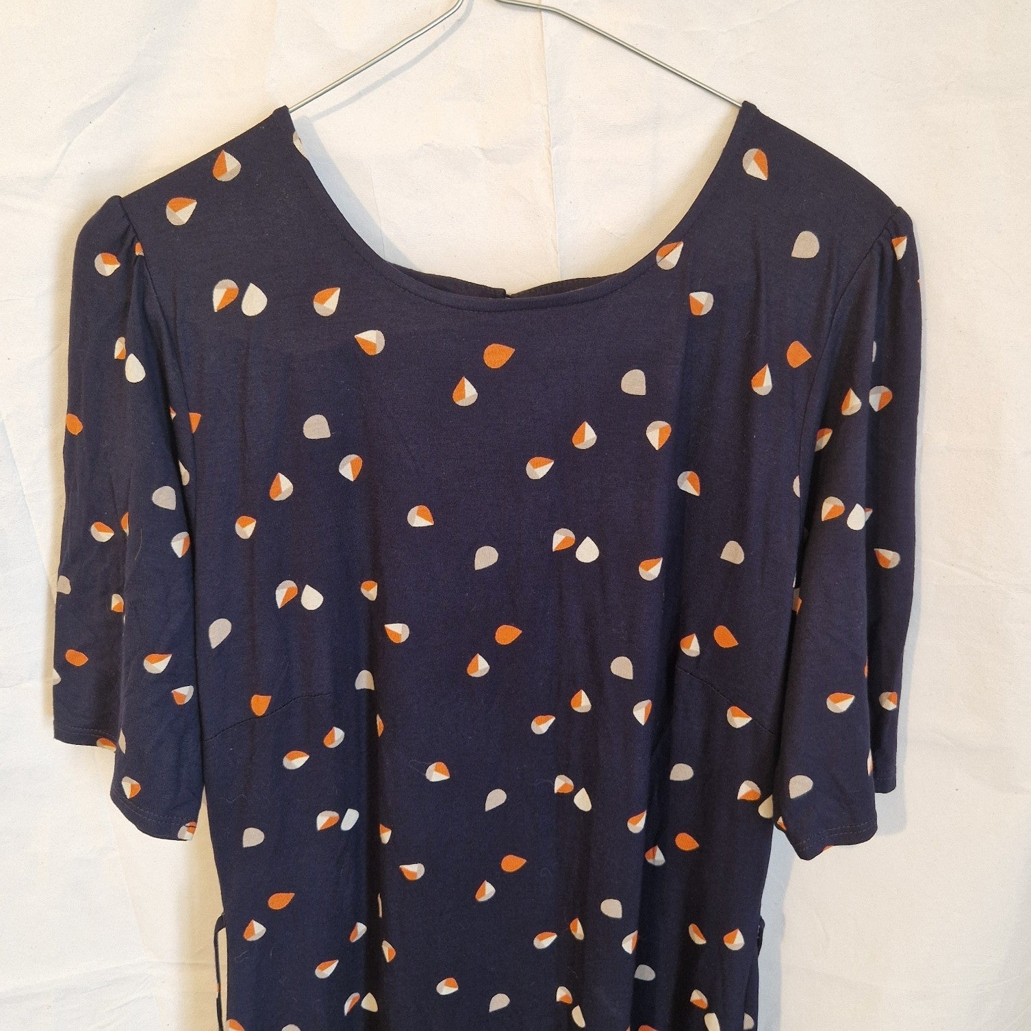 A navy blue fit and flare dress featuring a multicoloured petal print and short flared sleeves.