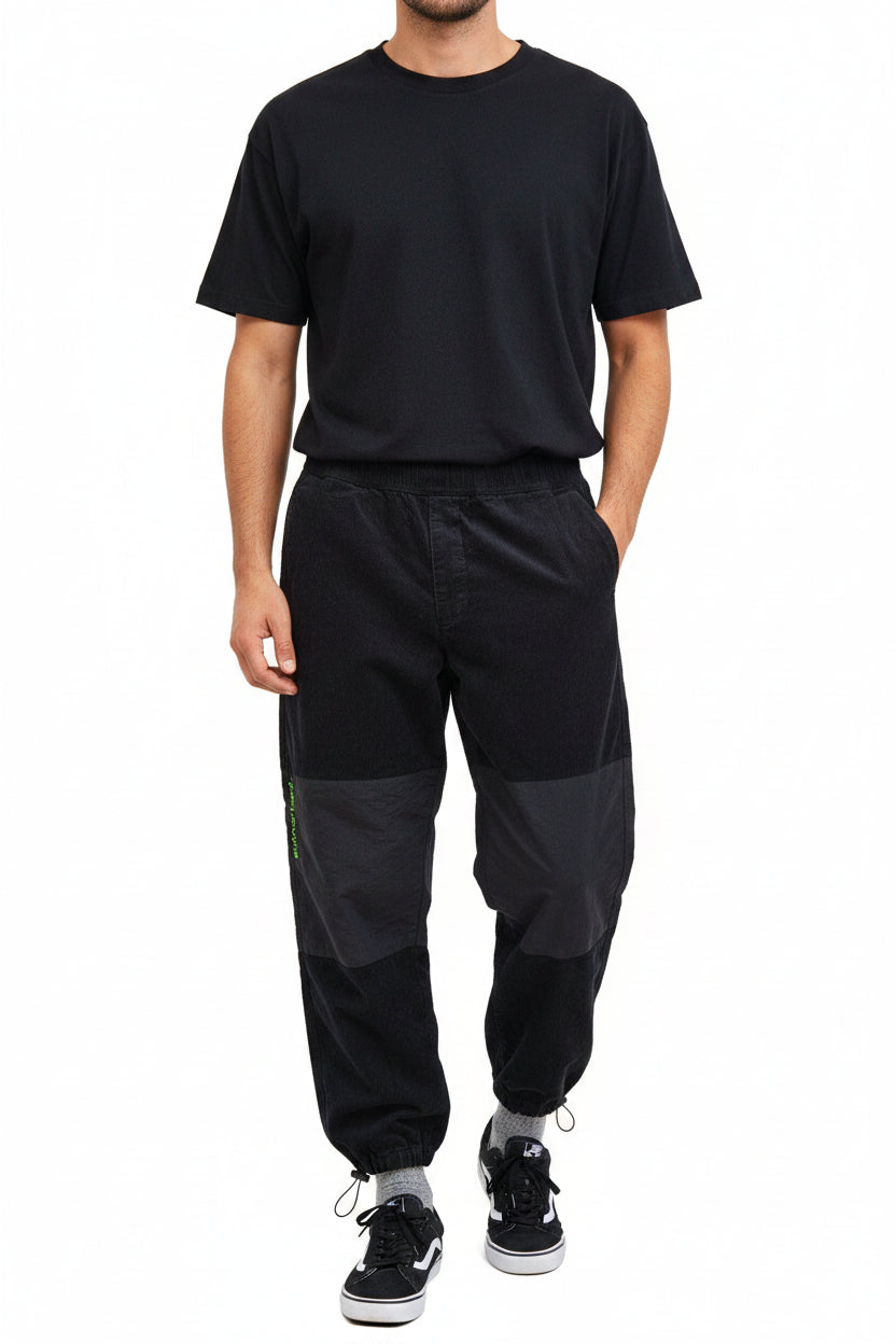 A man wears black Zara patchwork jogger cargo pants with a tapered fit and elastic cuffs.