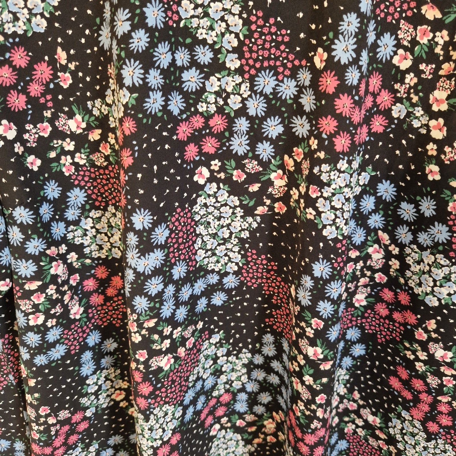 A black short-sleeve blouse featuring a vibrant multicoloured floral print.