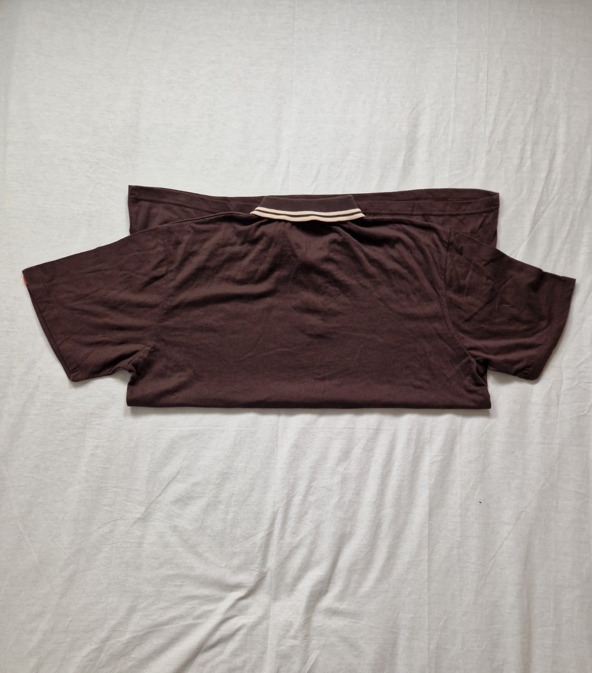 Brown t-shirt on a light gray bedspread