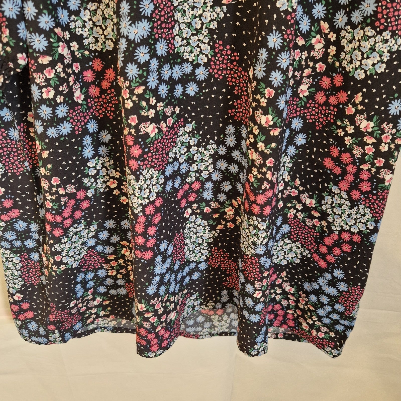 A black short-sleeved blouse featuring a vibrant multicoloured floral print.