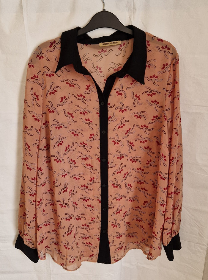 A long-sleeved, button-up chiffon blouse in peach with a black collar and a red floral pattern.