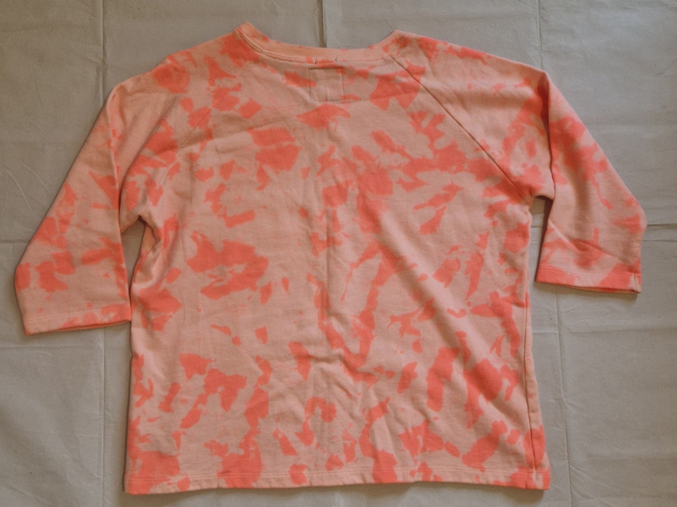 A pink and orange tie-dye cotton knit jumper with three-quarter length sleeves.