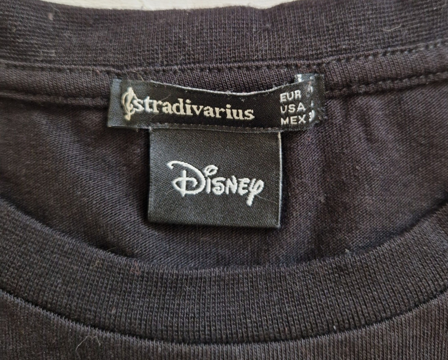 A close-up of the black fabric neck label featuring the Stradivarius and Disney logos.