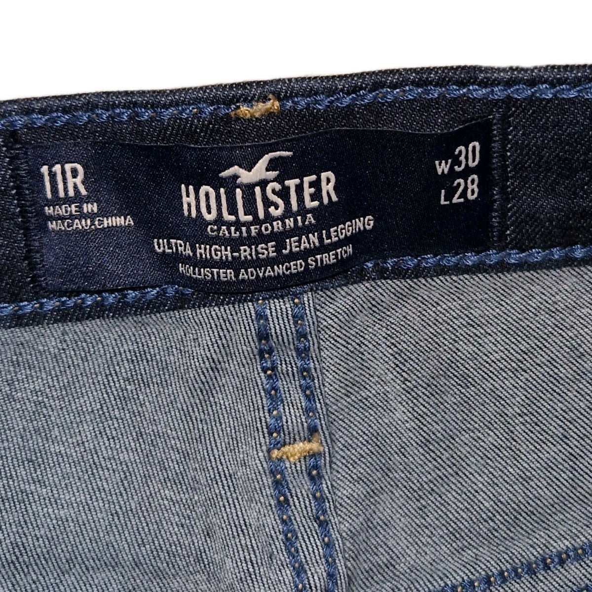A close-up of the interior waistband label on dark blue Hollister ultra high-rise jeans.