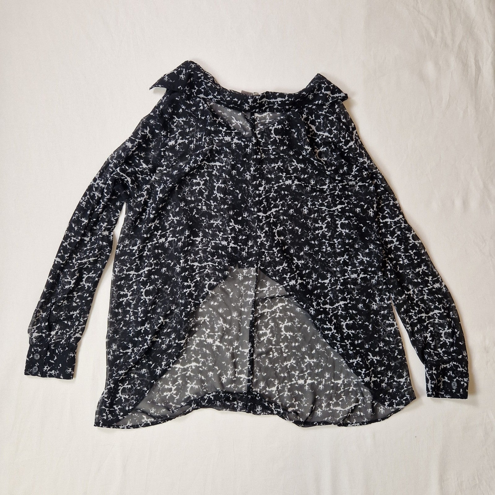 Black and white patterned blouse on a light beige background