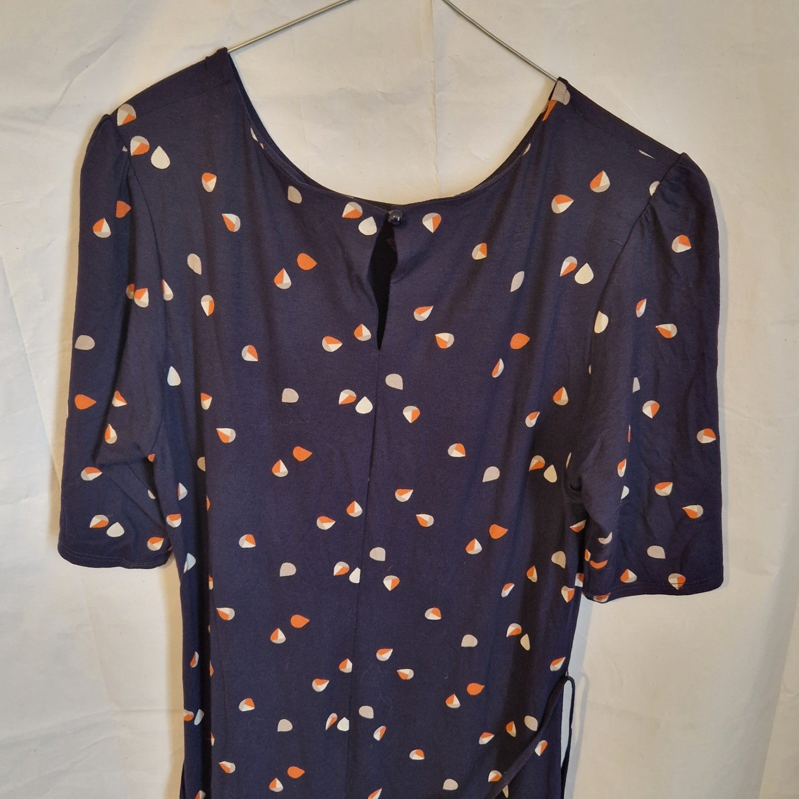 A navy blue fit and flare dress with a white and orange petal print and a back button closure.