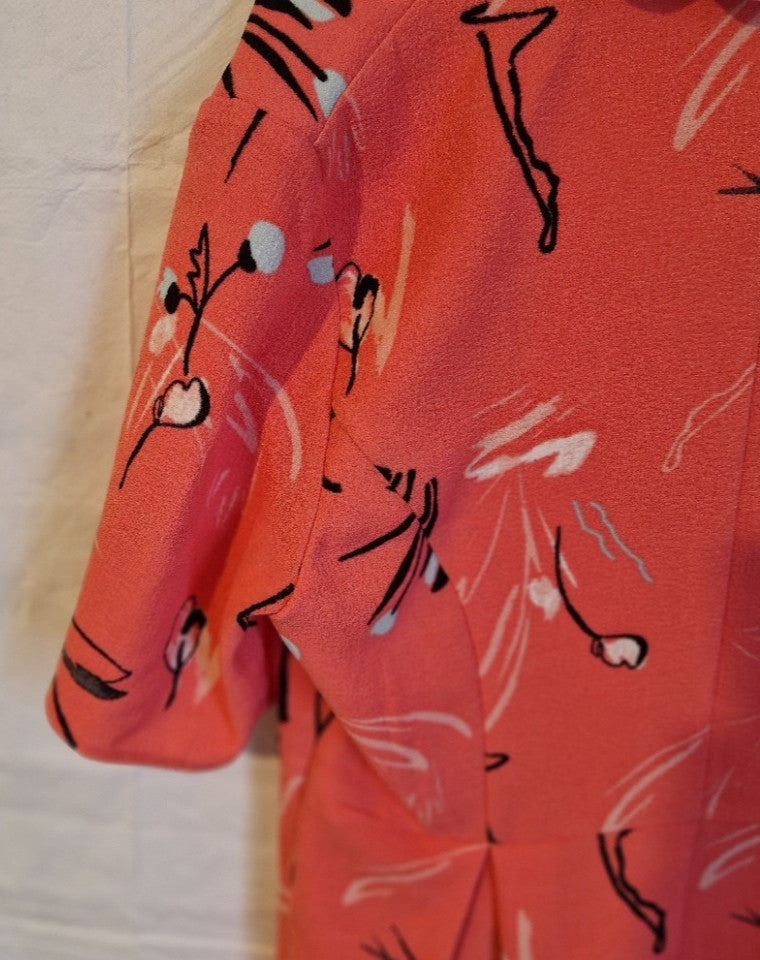 A close-up of a pink floral print dress with short cap sleeves and a fit and flare silhouette.