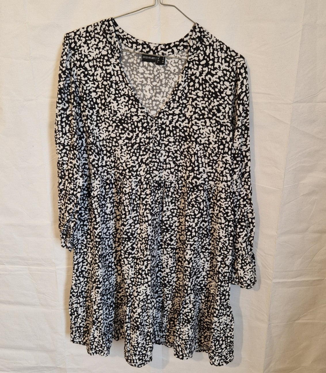 A black and white floral print midi dress with a V-neck and long sleeves.