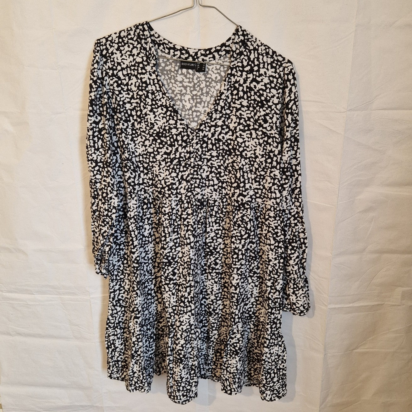 A black and white floral print midi dress with a V-neck and long sleeves.