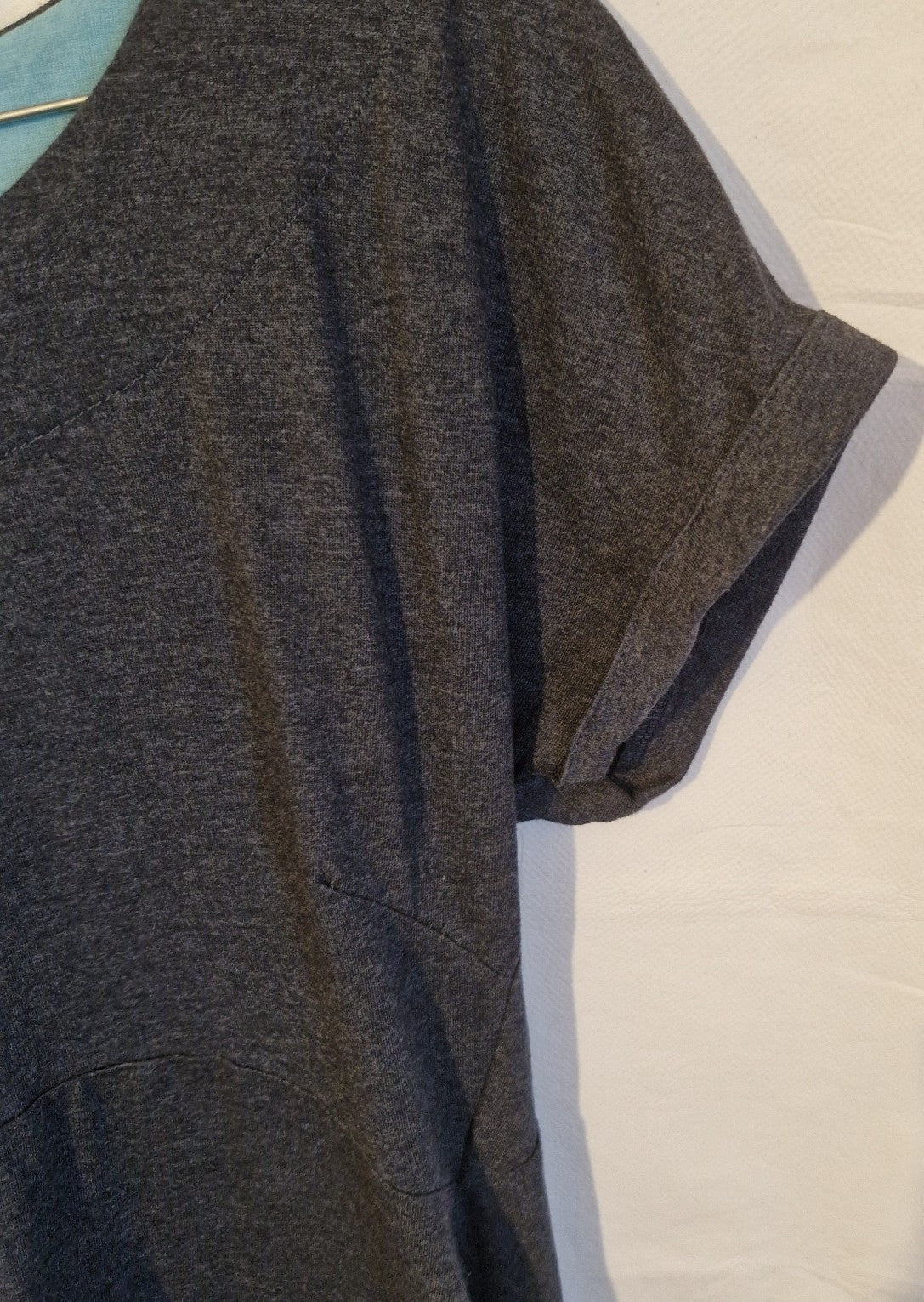 A close-up of a grey cotton blend jersey shift dress featuring a cuffed sleeve and seam detail.
