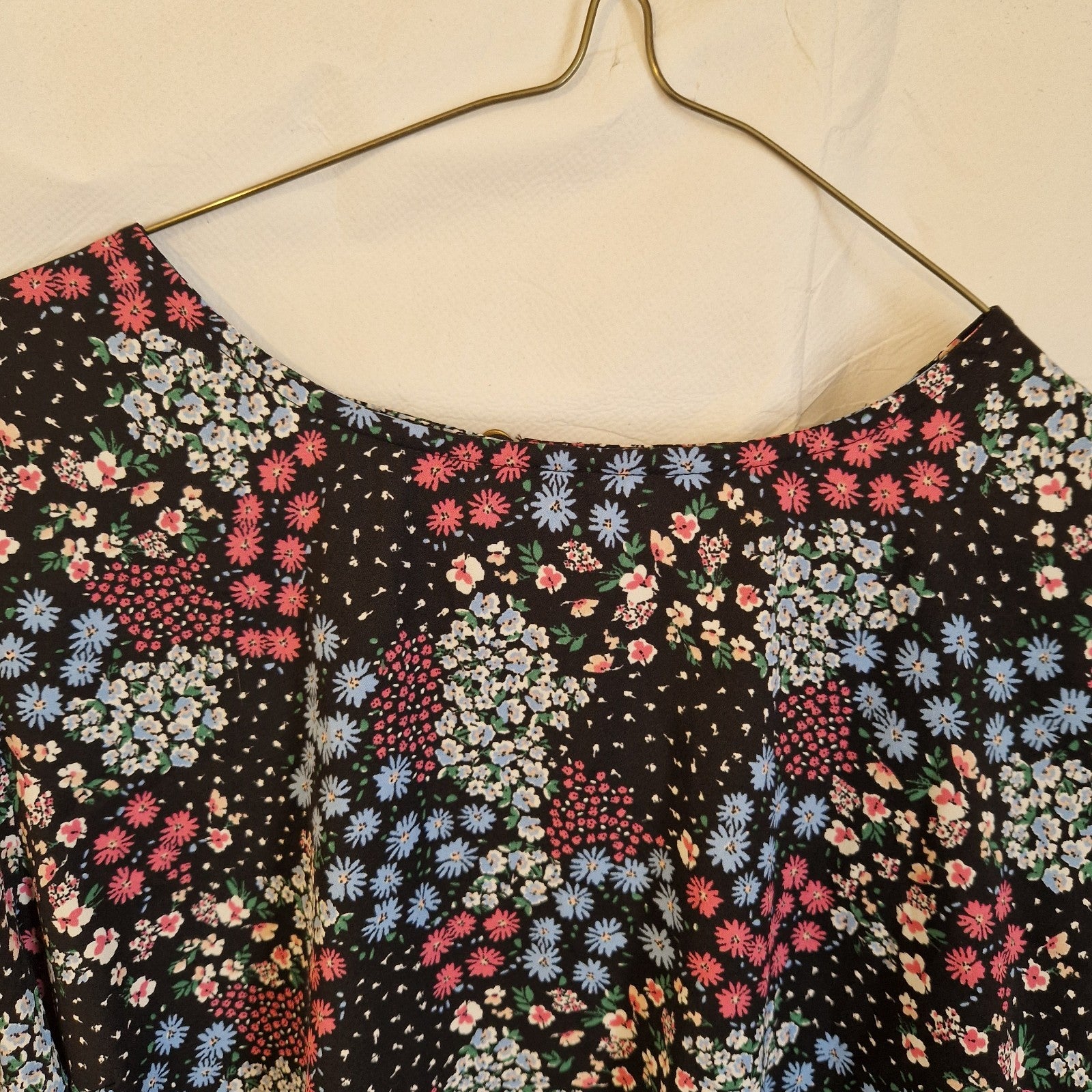 A black short-sleeved blouse featuring a vibrant multicoloured floral print and a round neckline.
