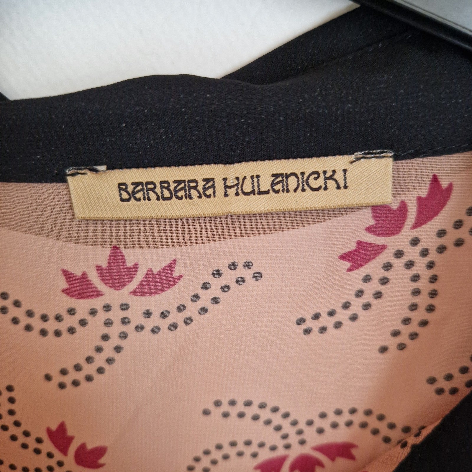A close-up of a Barbara Hulanicki label inside a black and pink floral chiffon blouse.