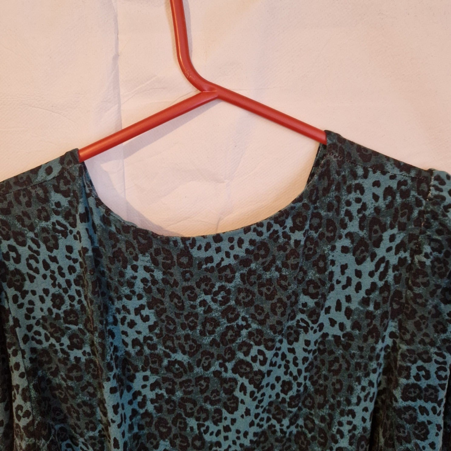 A teal and black leopard print long-sleeve maxi dress with a round neckline on a red hanger.