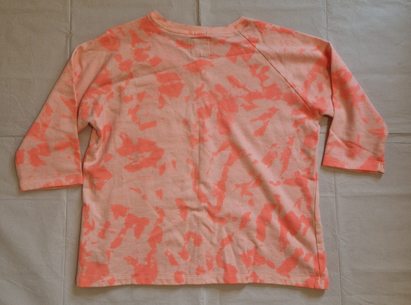 A pink and orange tie-dye cotton knit jumper with three-quarter sleeves.