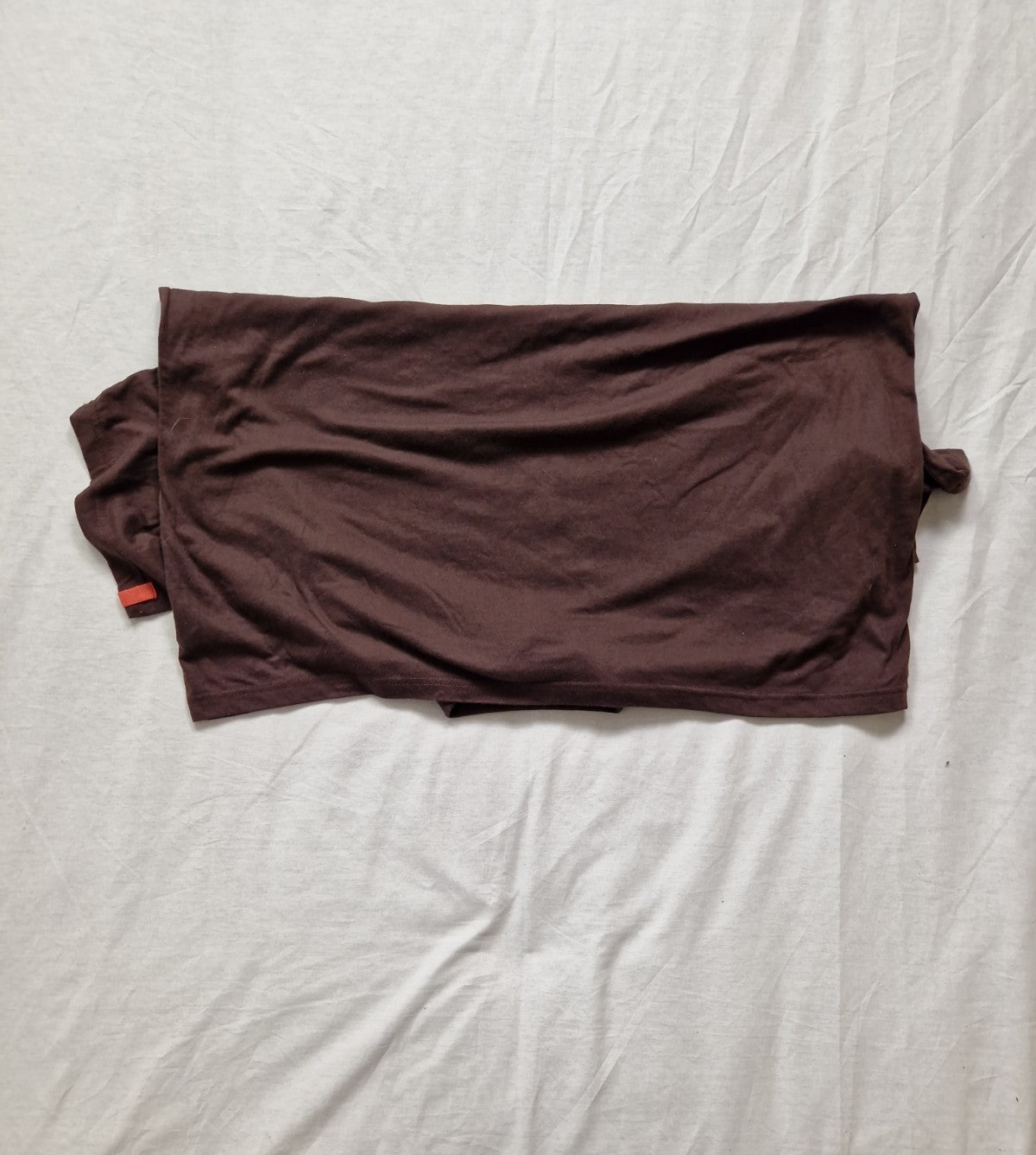 Brown t-shirt on a white bed