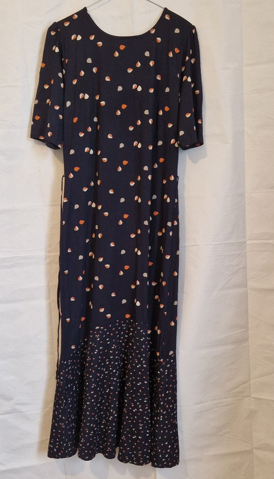 A navy blue fit and flare dress with a multicoloured petal print and a ruffled hem.