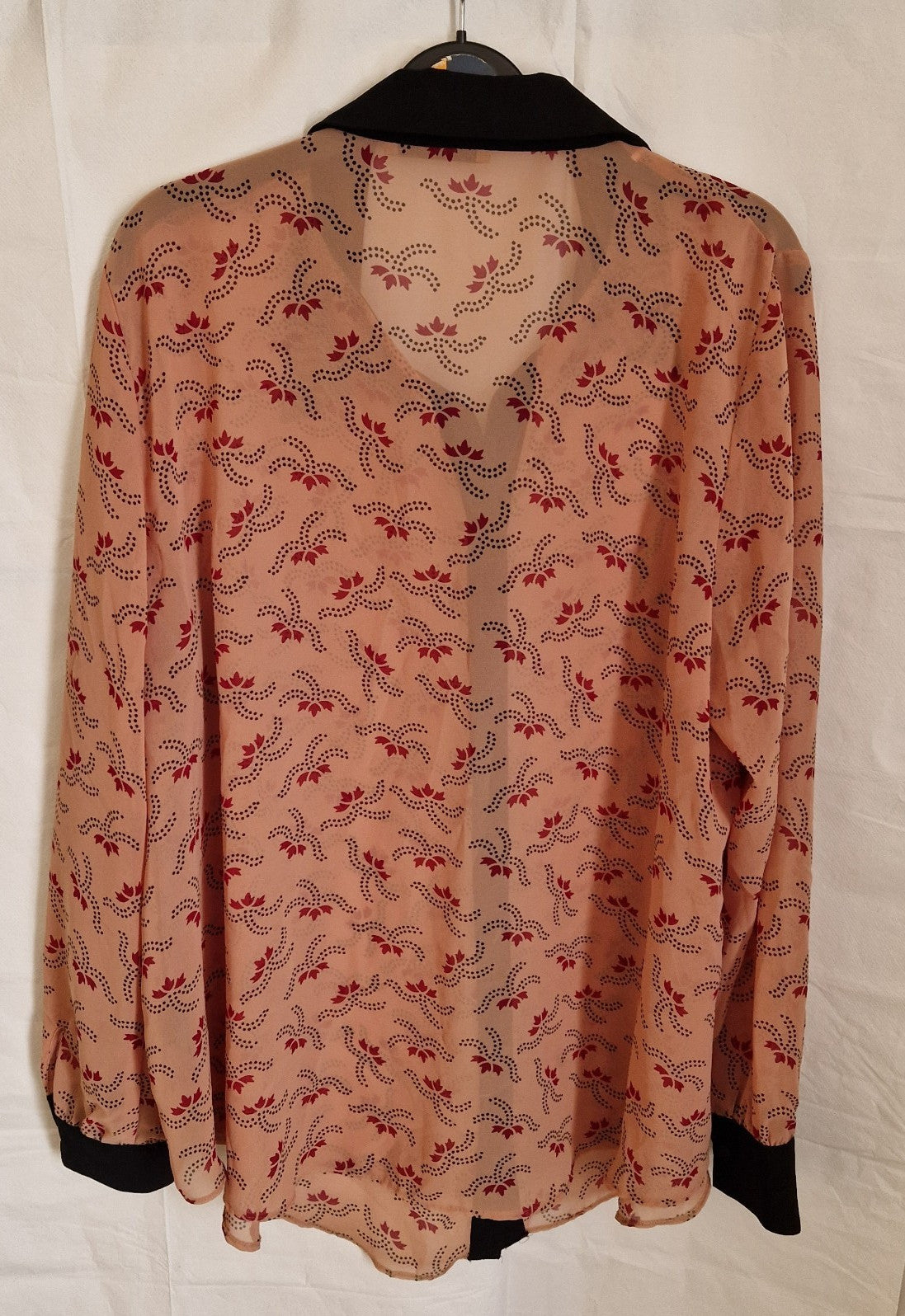 A long-sleeved George chiffon blouse in peach with a red floral pattern and black collar and cuffs.