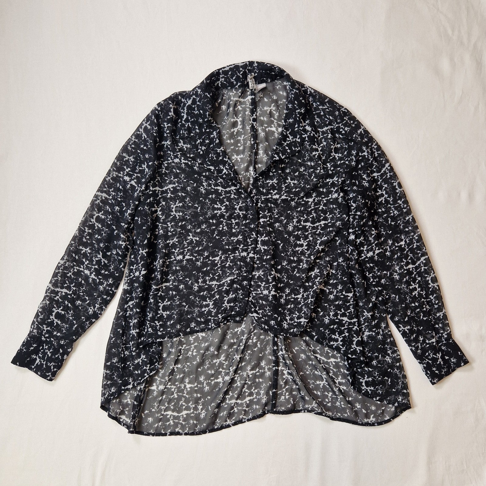 Black and white patterned blouse on a light beige background