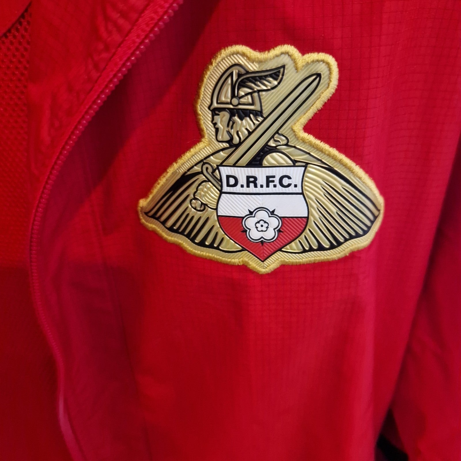A red FBT Doncaster Rovers training jacket featuring the club crest on the chest.