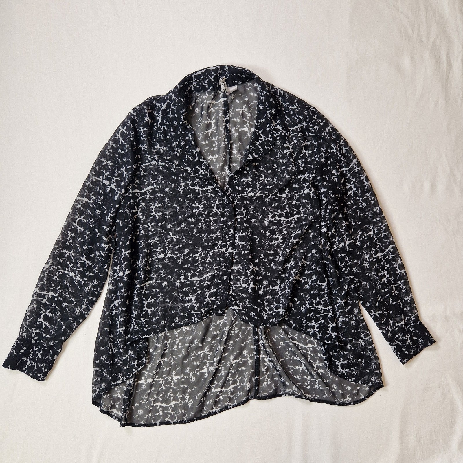 Black and white patterned blouse on a light beige background