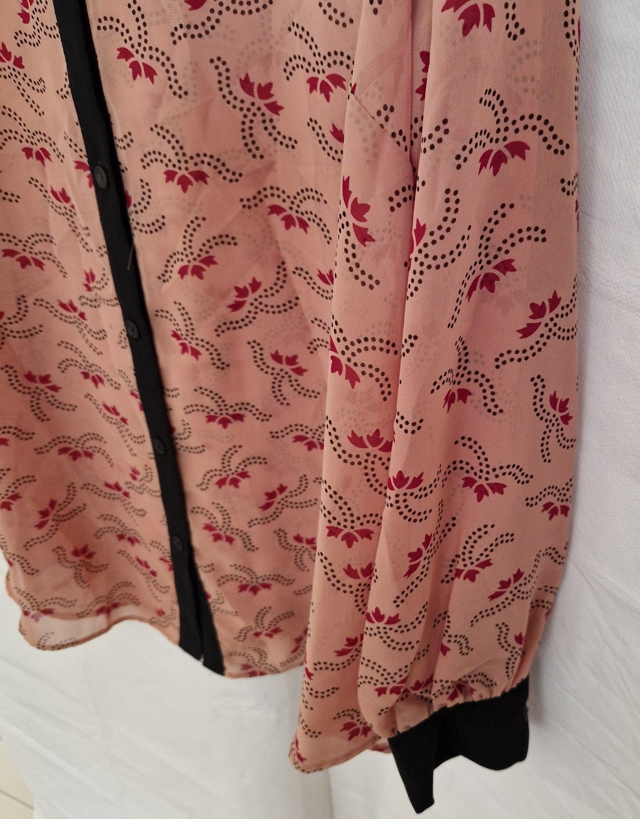 A peach-colored chiffon blouse with a black floral pattern, long sleeves, and a button-up front.
