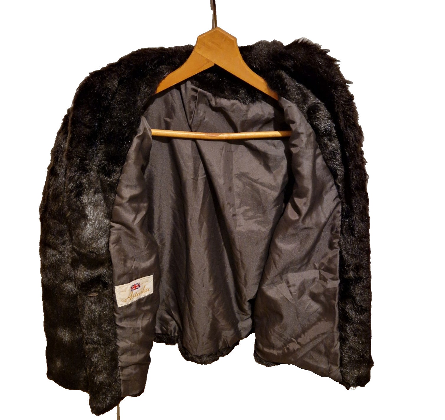 A dark brown Astraka vintage faux fur longline coat hanging on a wooden hanger.