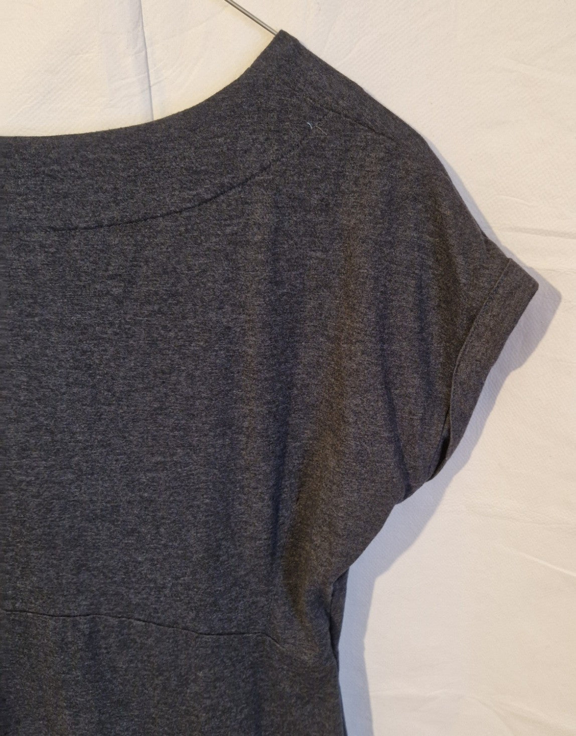 A close-up of the grey cotton blend jersey fabric showing the round neckline and short sleeves.