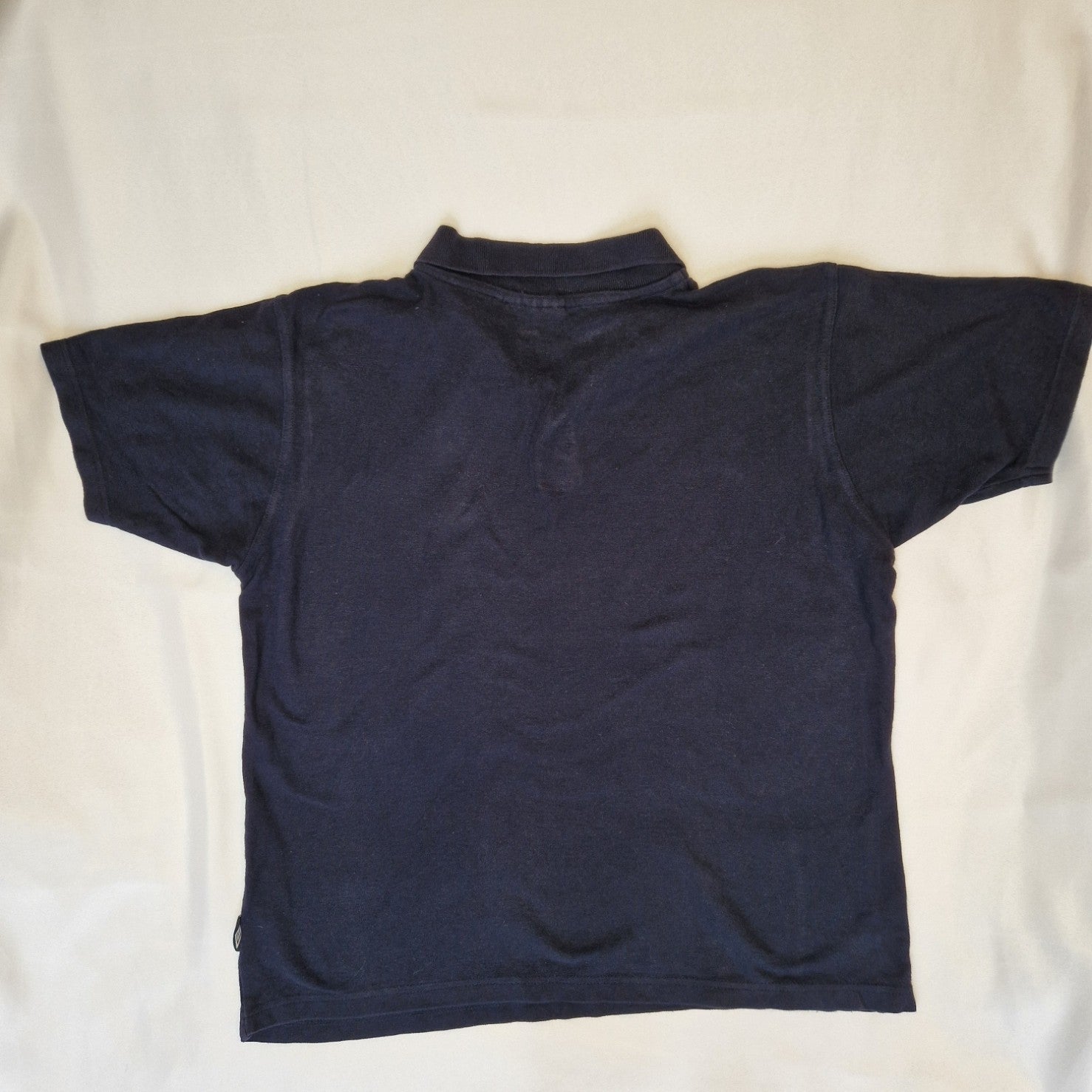 A navy blue Umbro short-sleeve polo shirt made from cotton jersey.