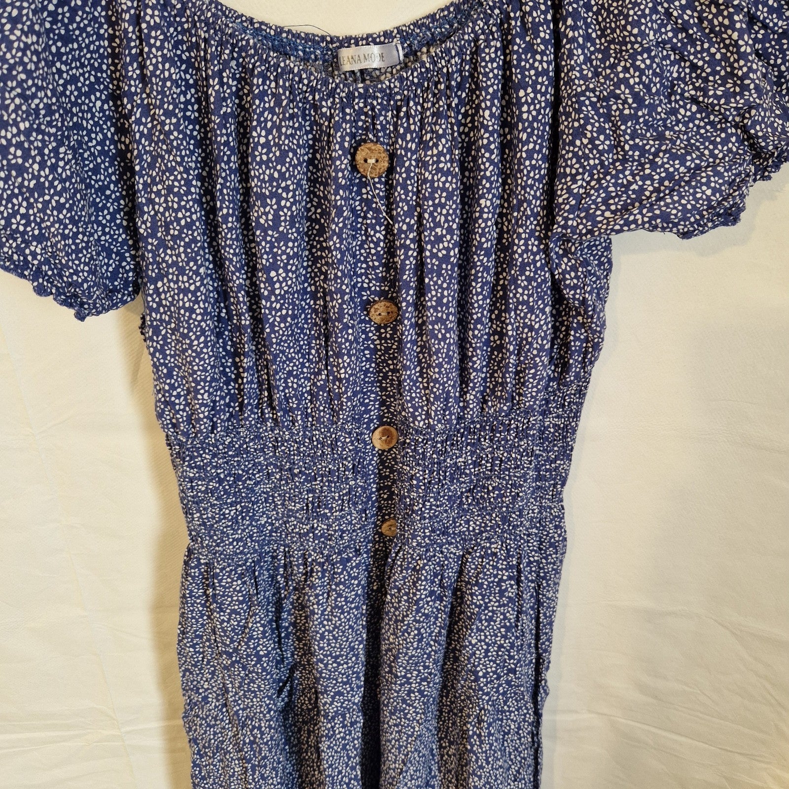 A blue knee-length dress by Leana Mode featuring a white floral pattern and button accents.