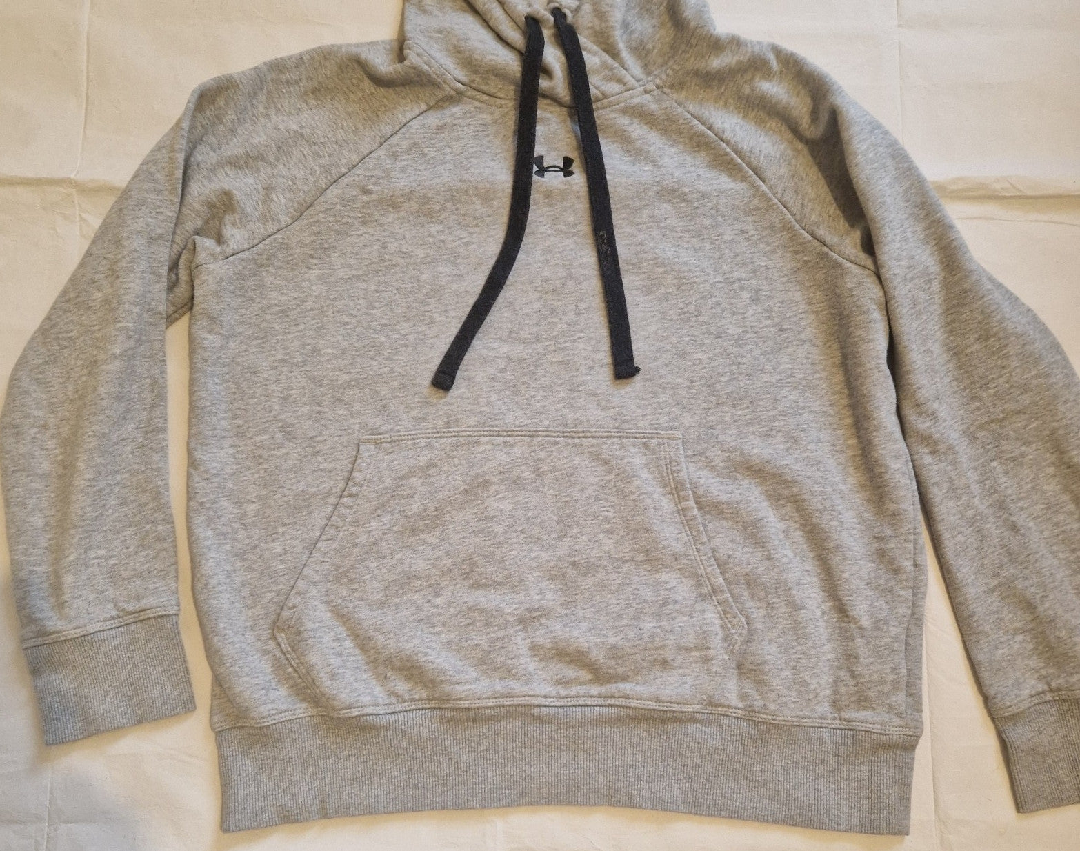 A grey Under Armour pullover hoodie for boys with a black logo and drawstring hood.