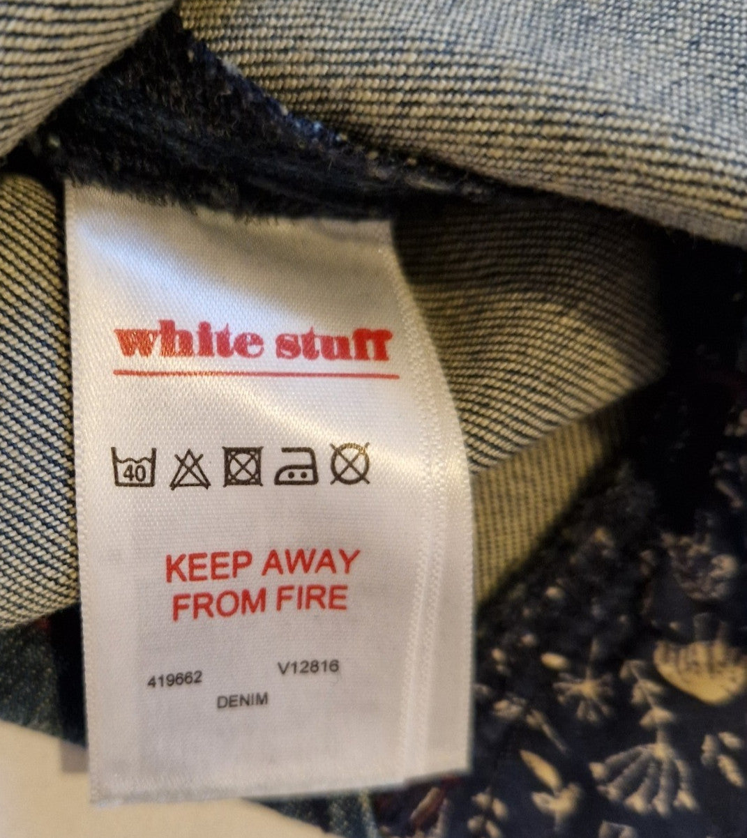 A close-up of a White Stuff clothing label inside a dark blue denim skirt.