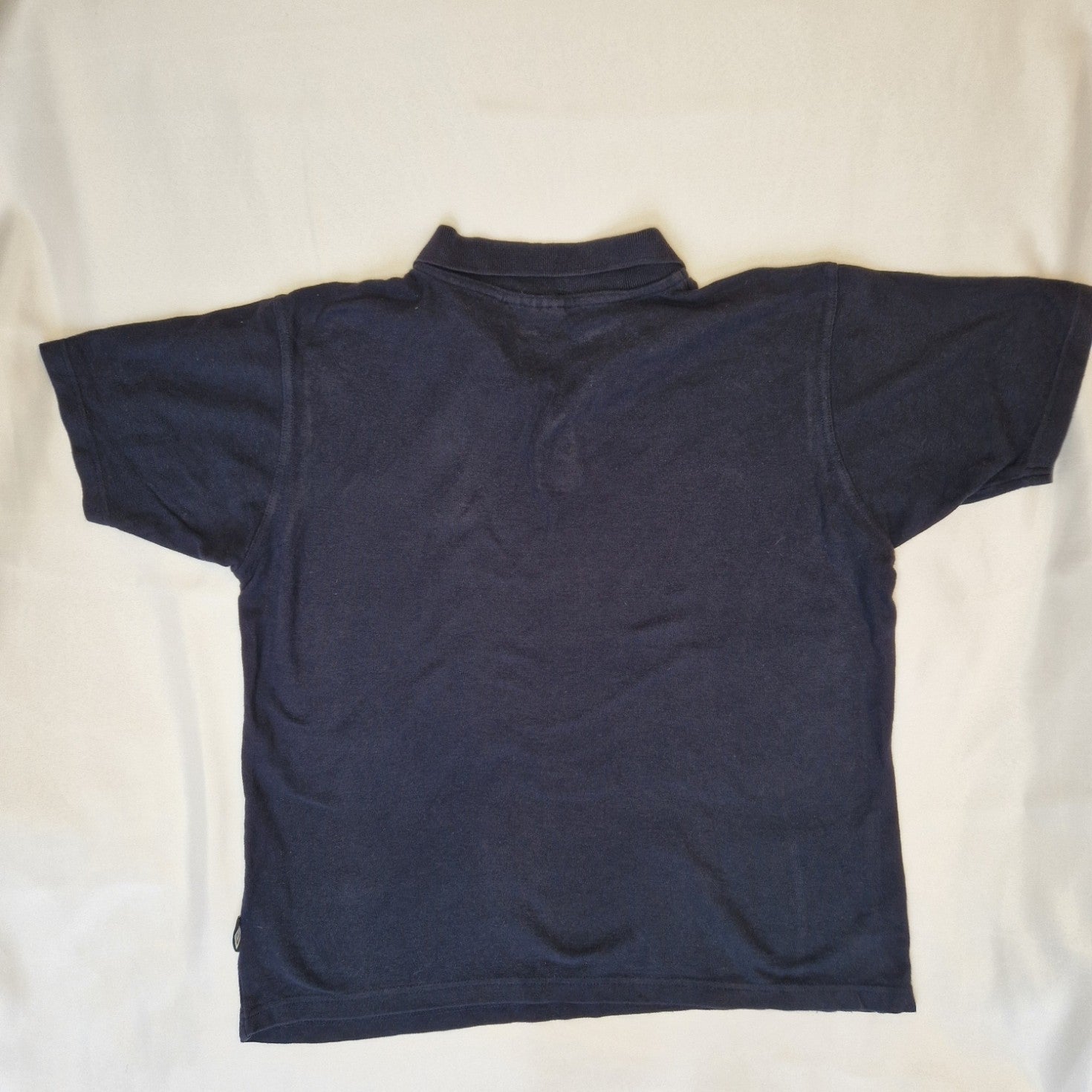 A navy blue Umbro short sleeve polo shirt made from cotton jersey.