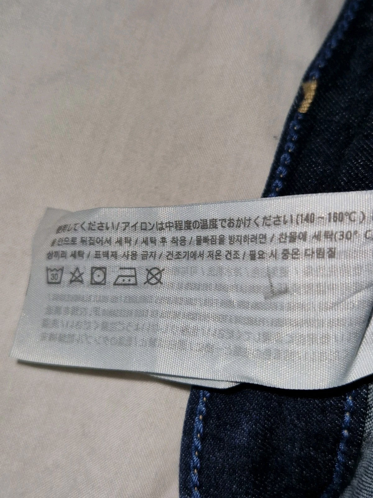A close-up of a Hollister jeans care label with washing instructions in Japanese and Korean.