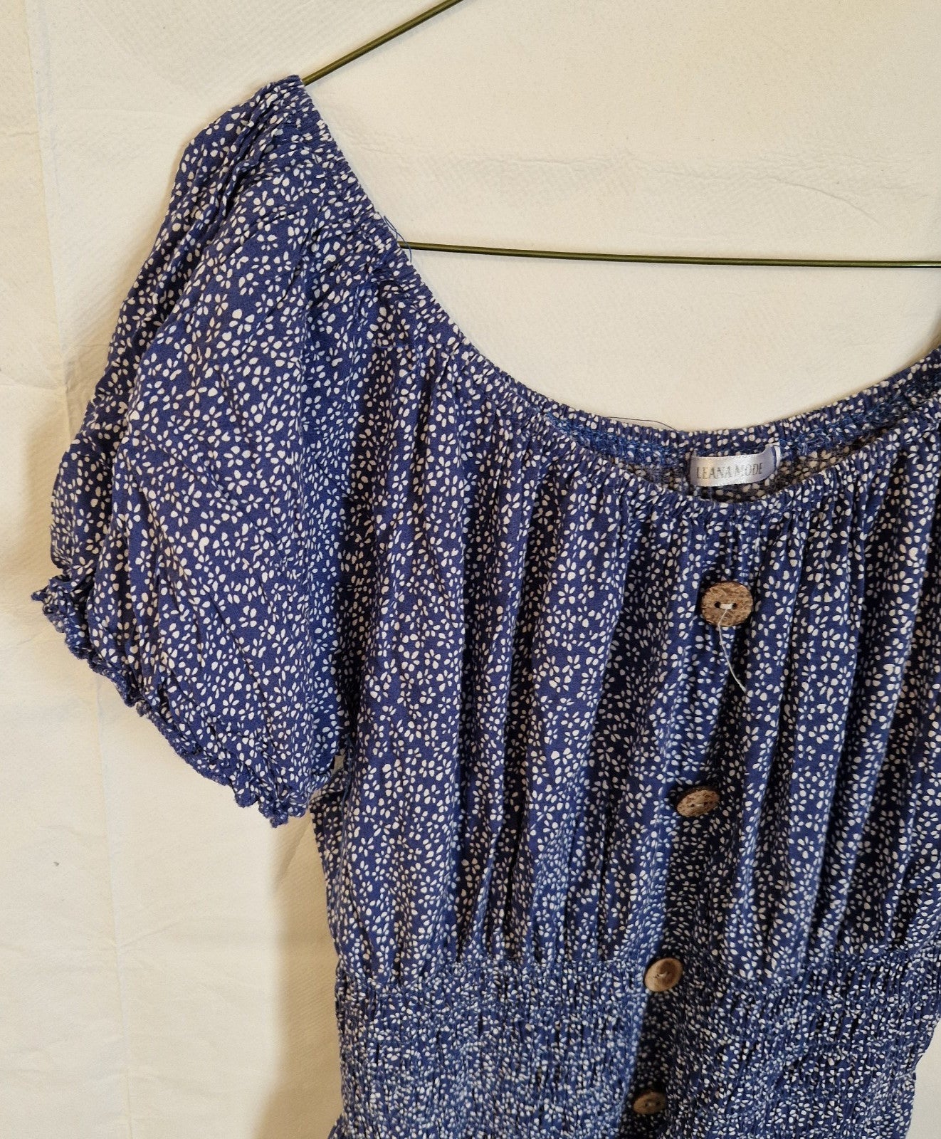 A blue knee-length dress by Leana Mode featuring a white floral print and button-front detail.