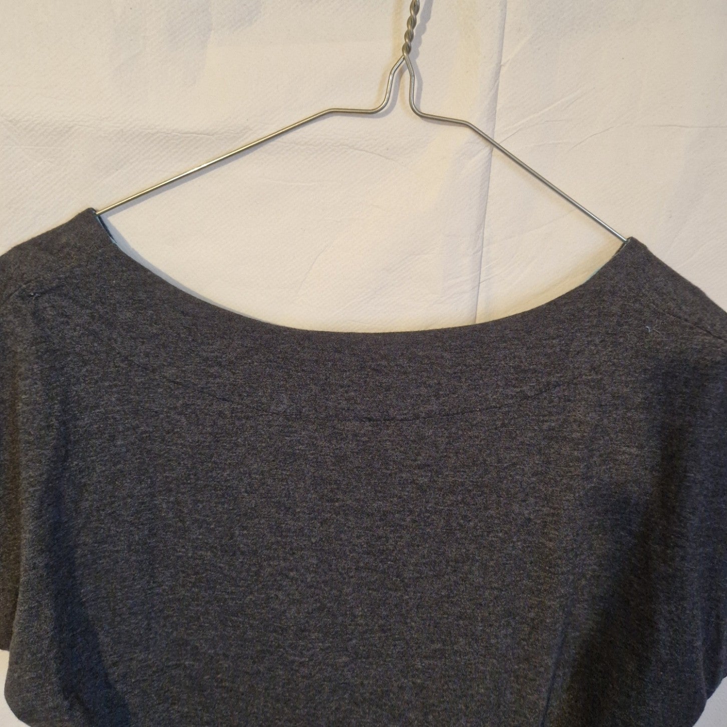 A close-up view of the round neckline of a grey cotton blend midi shift dress on a hanger.