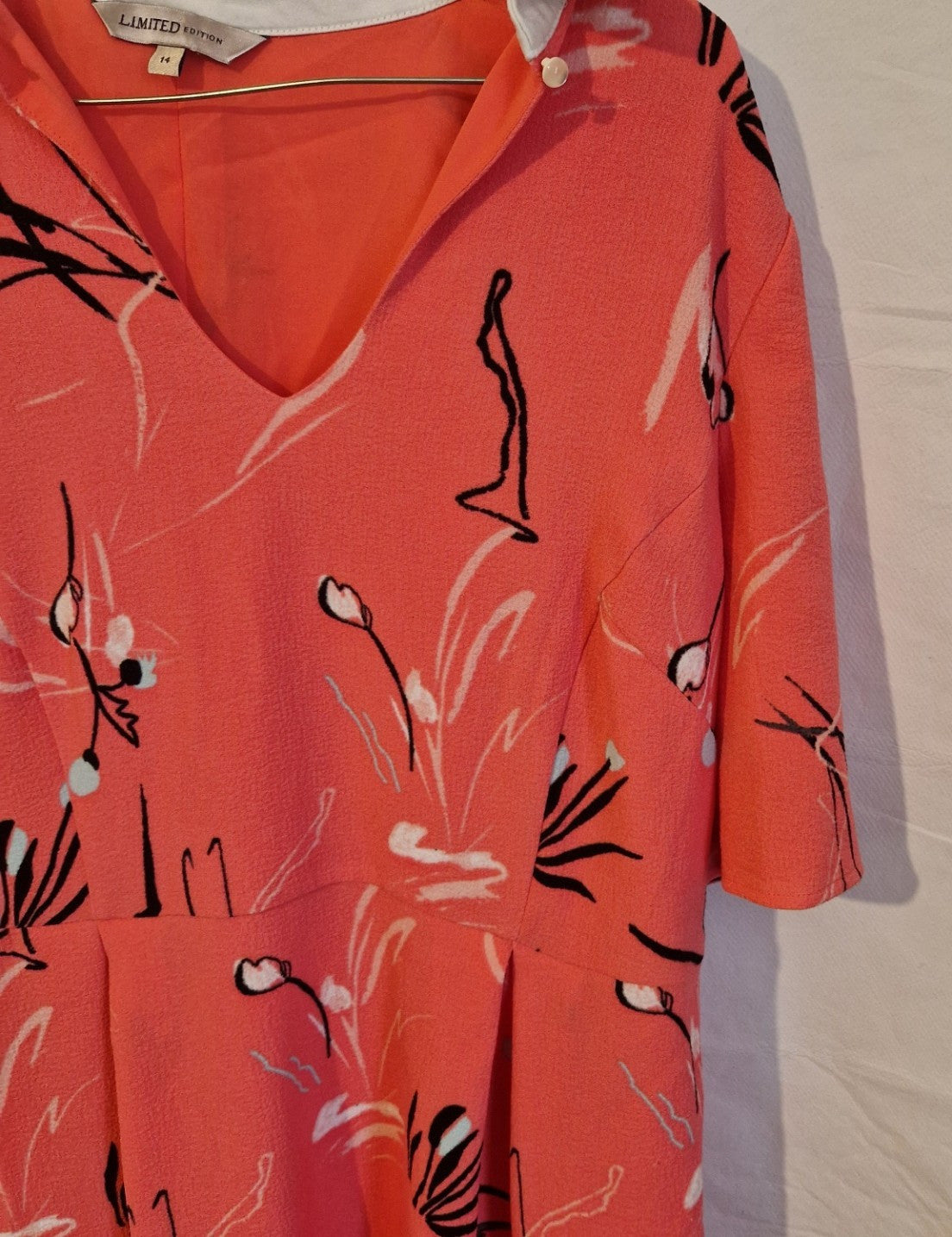 A coral pink fit and flare dress featuring a black and white abstract floral print.