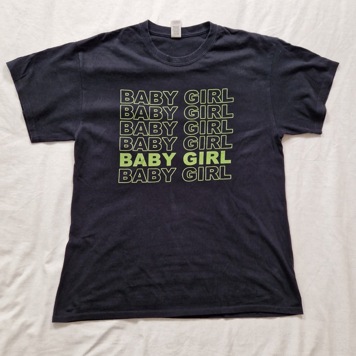 Black t-shirt with 'BABY GIRL' text printed in green on a white background
