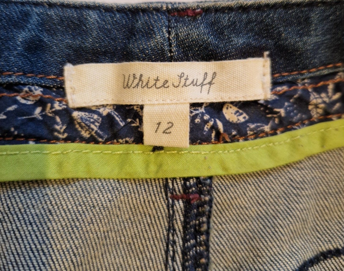 A close-up of a White Stuff brand label on a dark blue denim skirt, size 12.