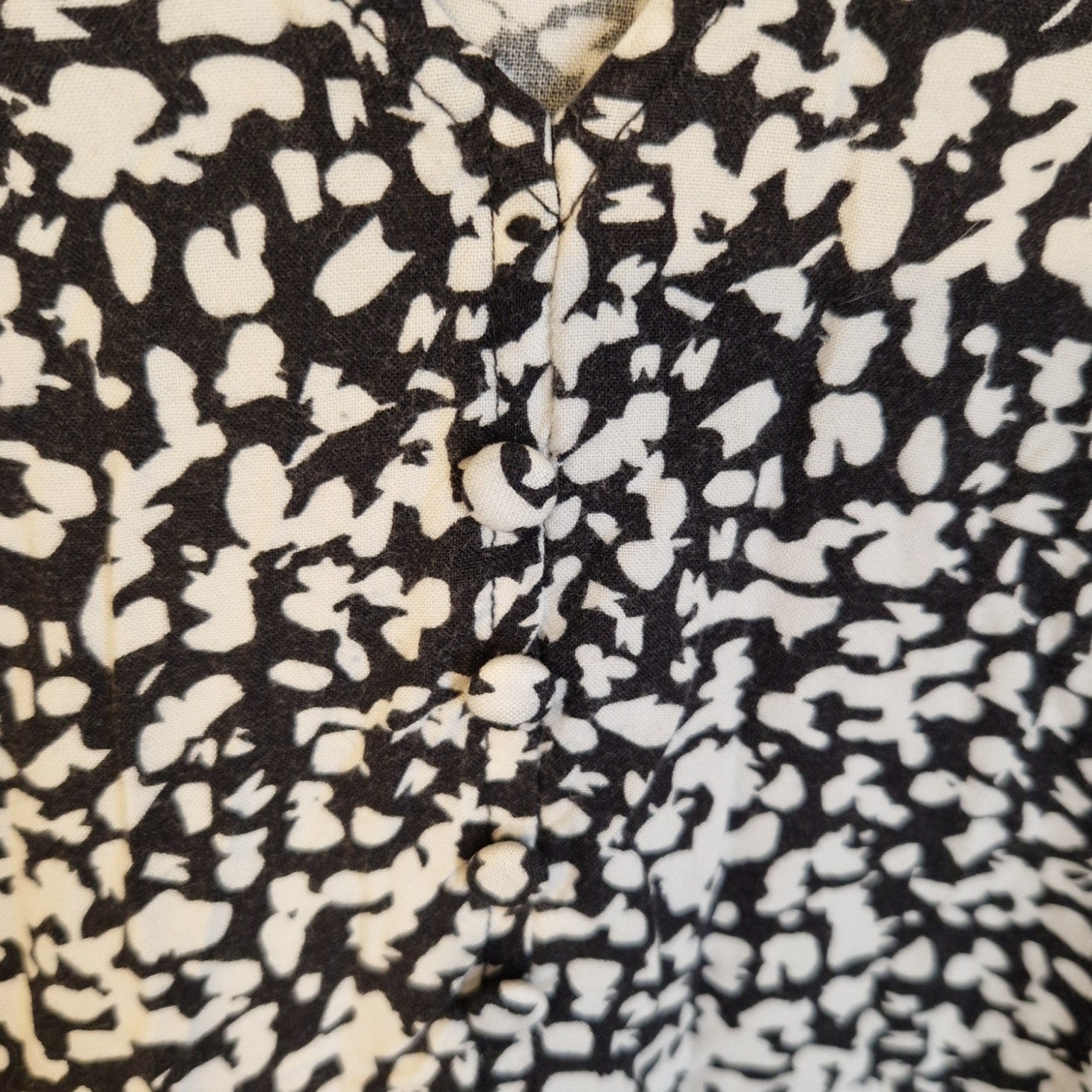 Close-up of a black and white floral midi dress featuring fabric-covered buttons down the front.