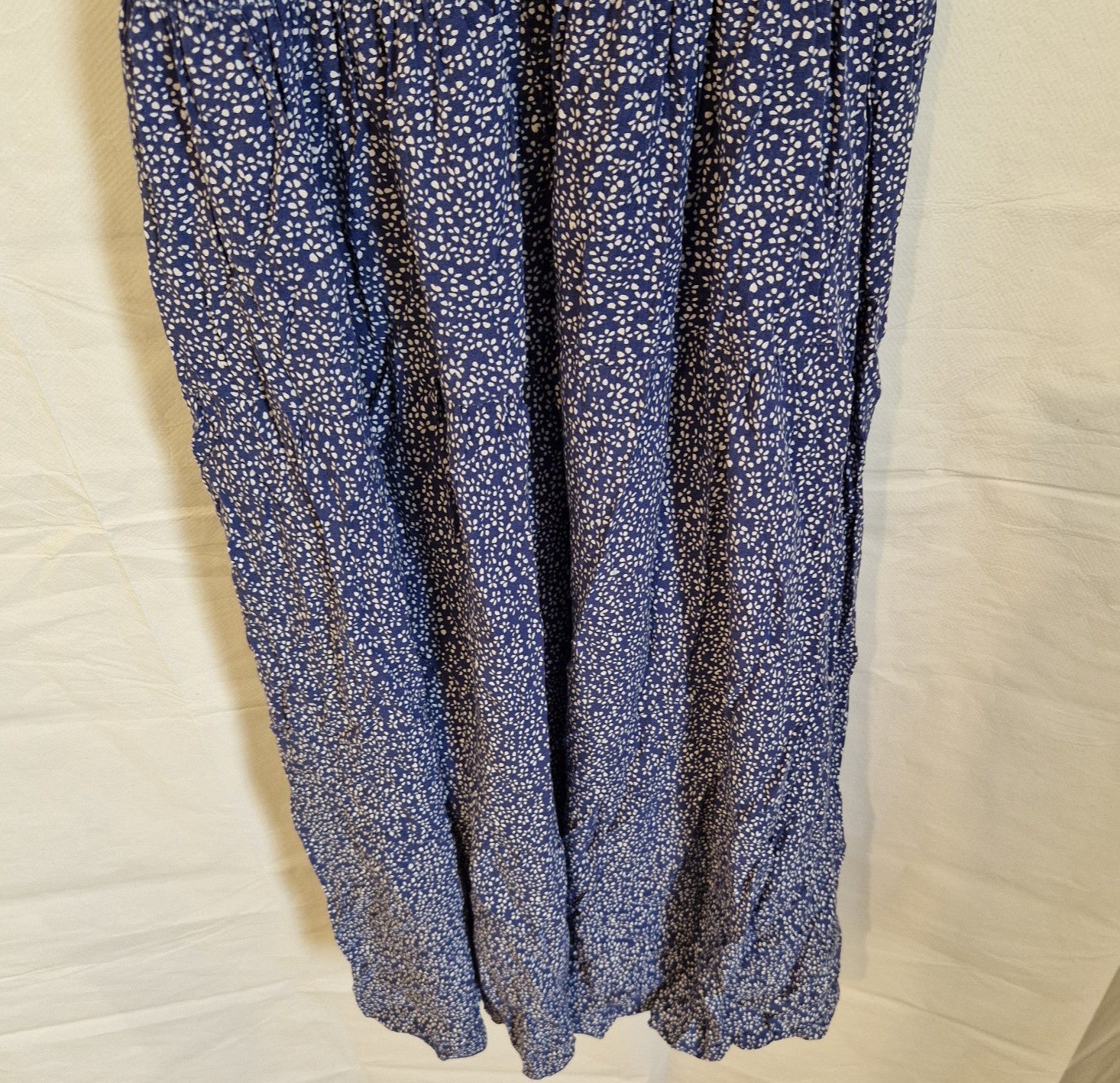 A blue knee-length dress with a white floral pattern and a gathered skirt.