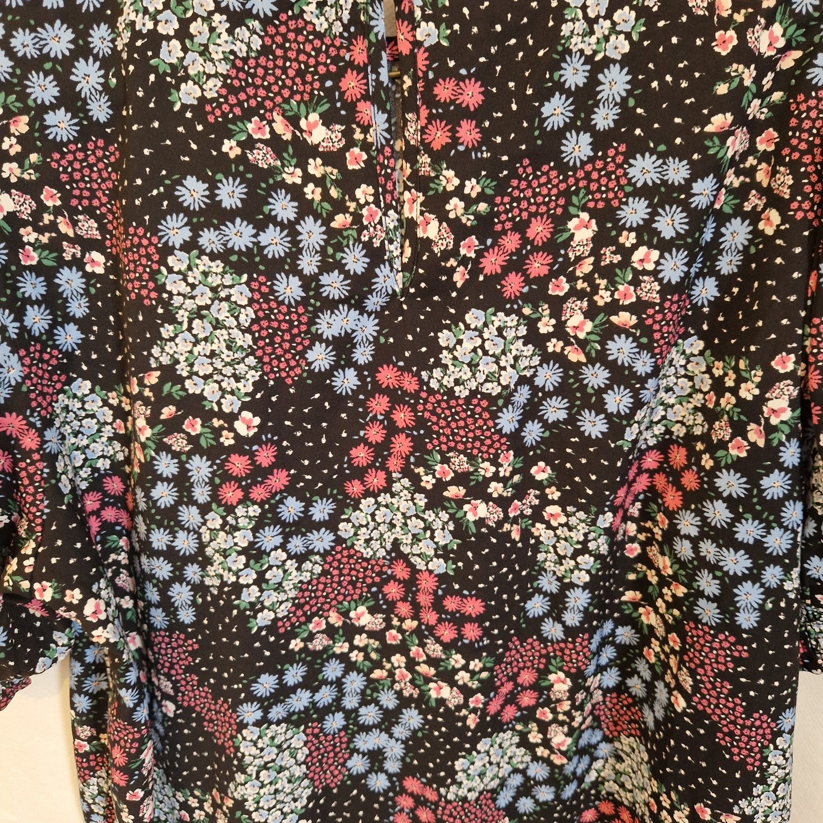 A black short-sleeve blouse featuring a vibrant multicoloured floral print and a round neckline.