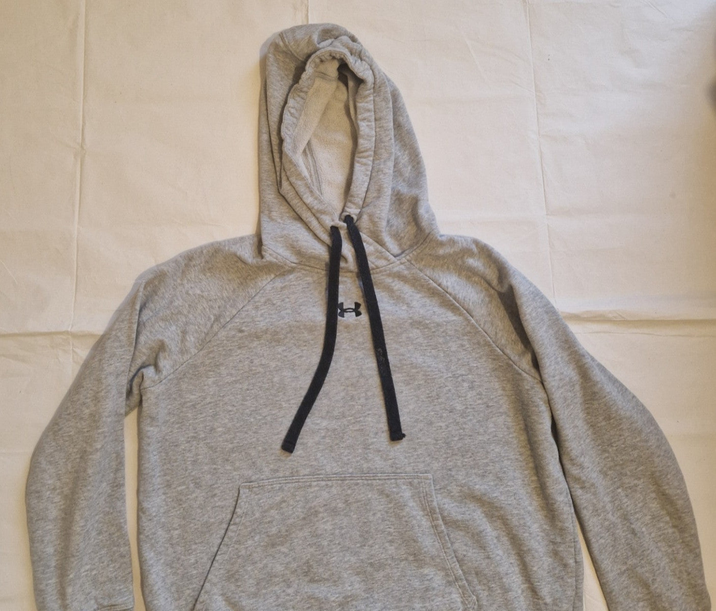 A grey Under Armour pullover hoodie for boys with a black logo and drawstring hood.