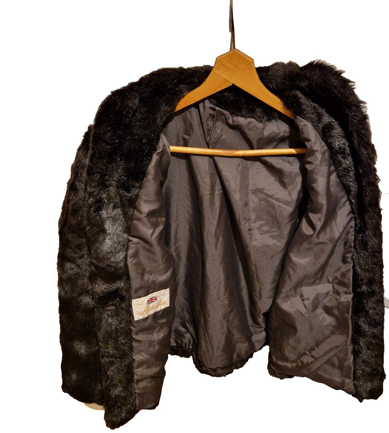 A dark brown Astraka vintage faux fur longline coat hanging on a wooden hanger.