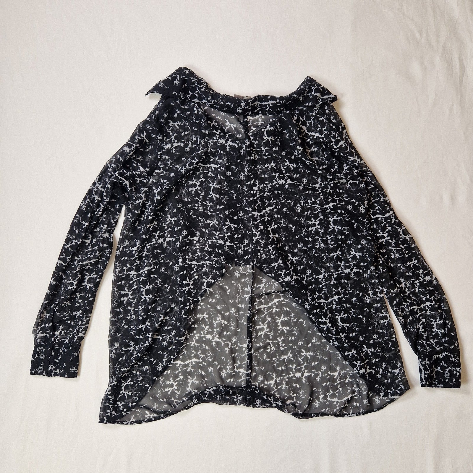 Black and white patterned blouse on a light beige background