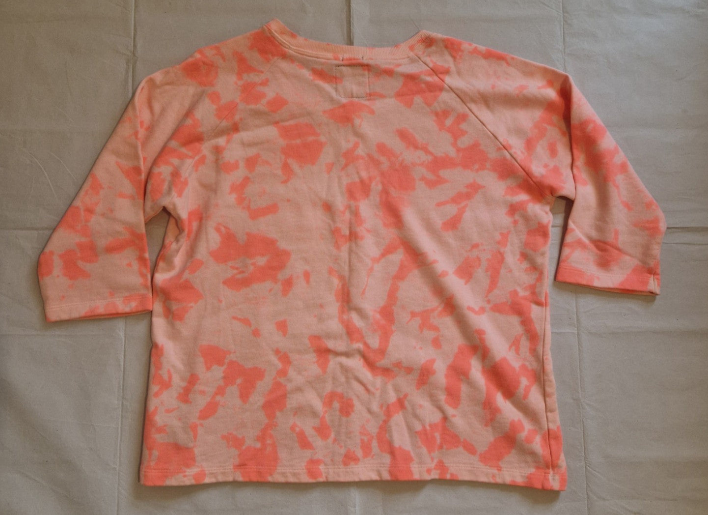 A pink and orange tie-dye cotton knit jumper with three-quarter length sleeves.